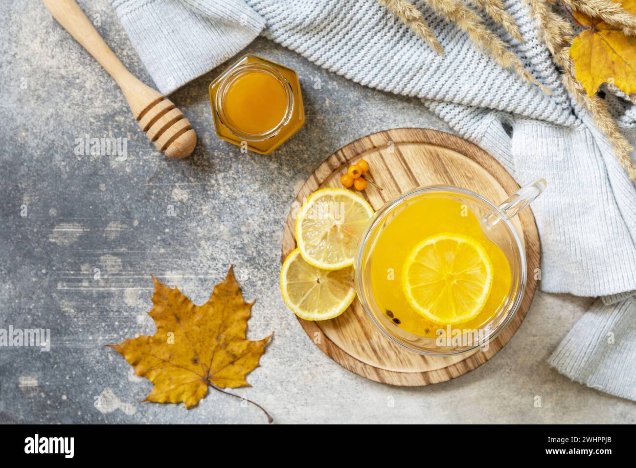 Thé chaud d'argousier vitaminé à base de plantes dans une tasse en verre avec des baies d'argousier fraîches, du miel et du citron sur une table en pierre. Détendez-vous Banque D'Images