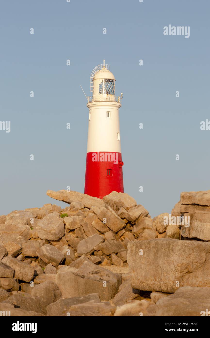 Phare de Portland Bill dans la lumière du coucher du soleil. Prise de vue verticale. Rochers devant. Banque D'Images