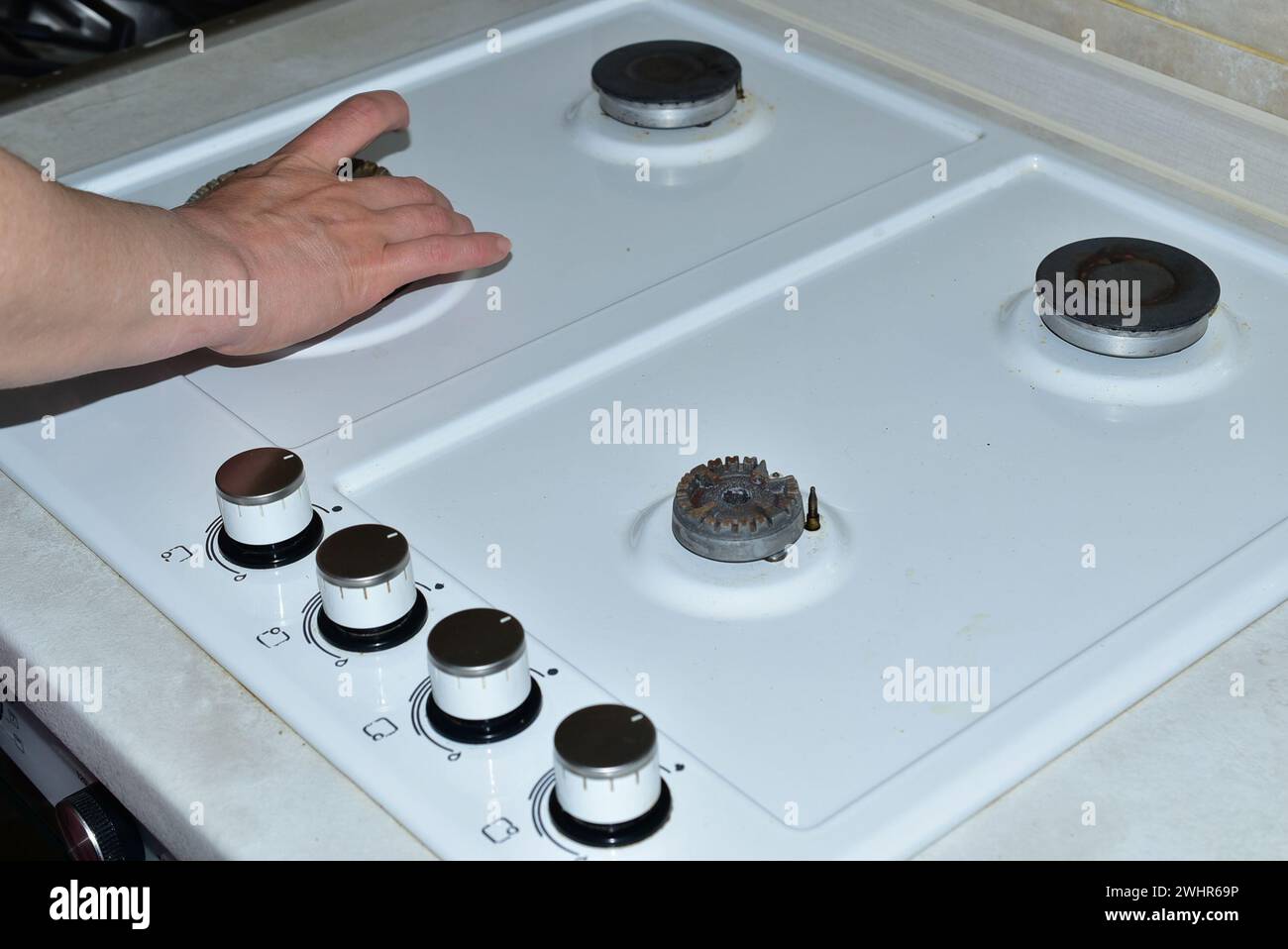 Sur l'image, la main d'une femme enlève les brûleurs avant de commencer à laver la surface de la cuisinière à gaz. Banque D'Images