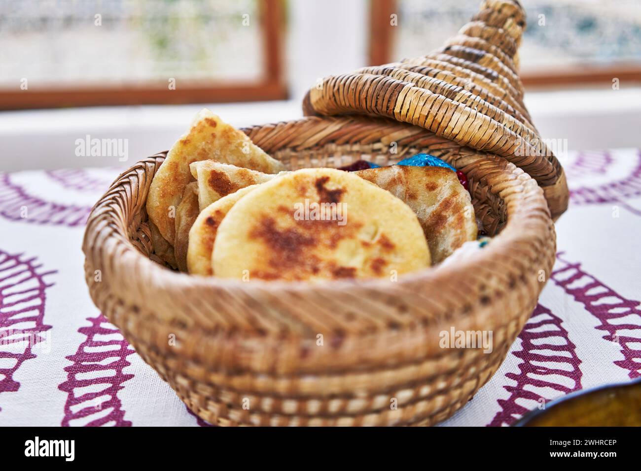 Un panier à pain marocain traditionnel en osier rempli de khobz frais sur une nappe brodée. Banque D'Images