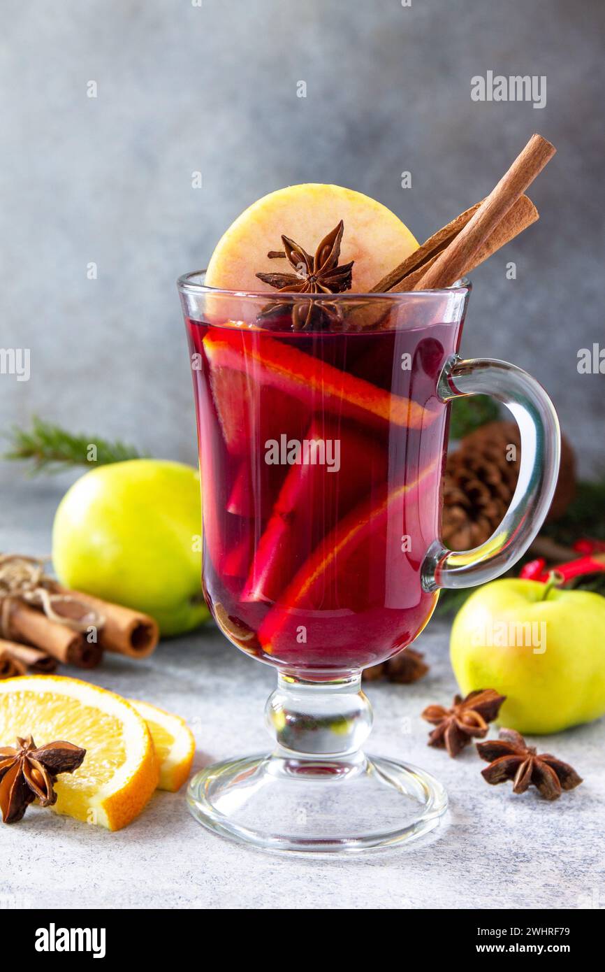 Vin chaud de Noël, boisson alcoolisée d'hiver. Un verre de vin chaud (gluhwein) et ses ingrédients sur fond de pierre. Banque D'Images