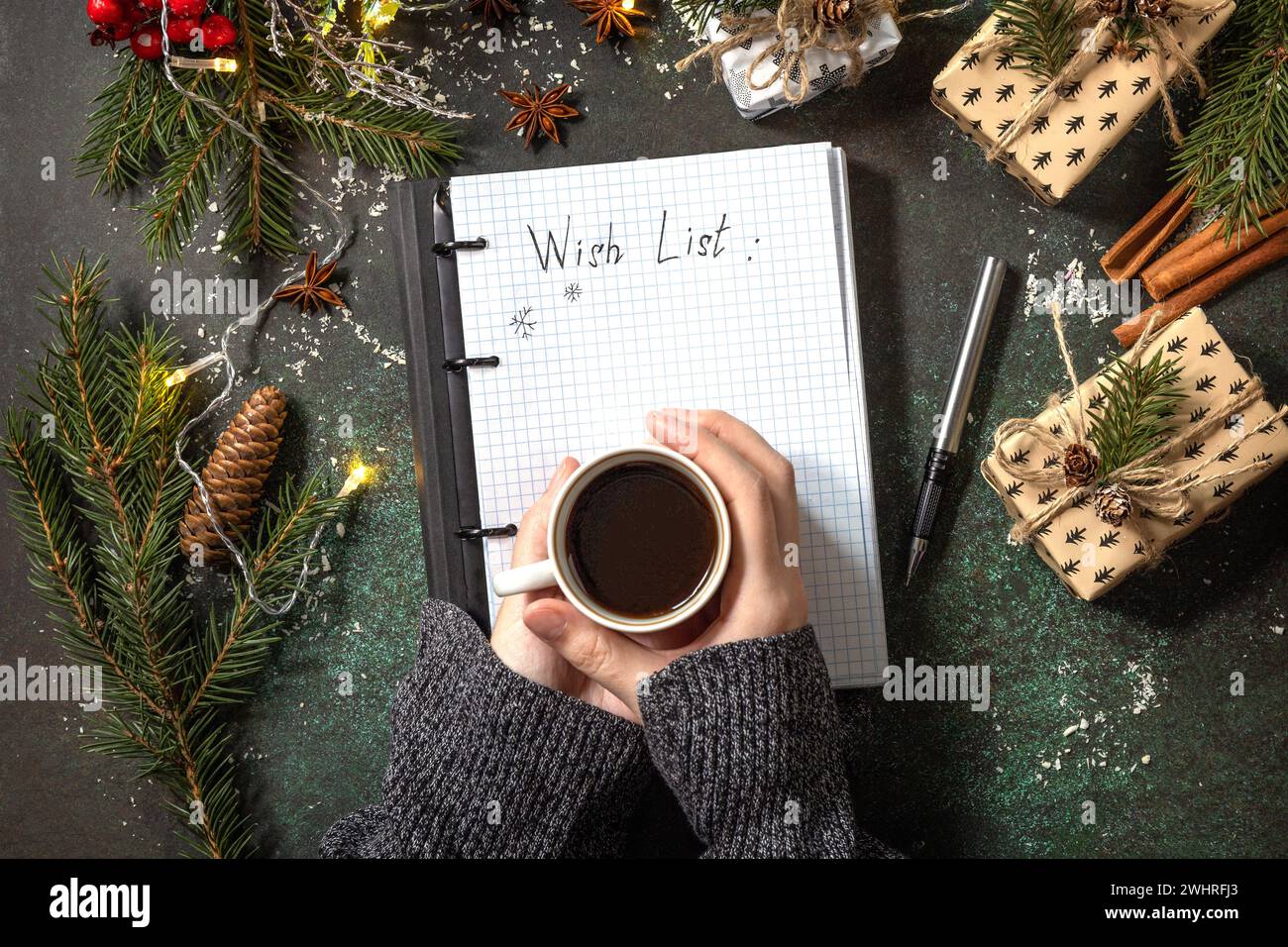 La femme écrit dans un cahier avec une liste vide et une tasse de café sur le dessus de table en pierre sombre de Noël. Contexte des objectifs du nouvel an. Plat Banque D'Images