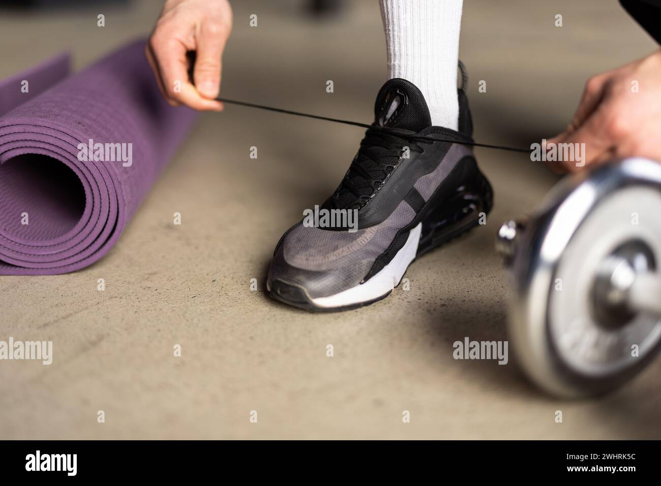 Gros plan sur l'homme dans les vêtements de fitness sur les baskets à fixation à domicile avant de faire de l'exercice avec les poids des mains Banque D'Images
