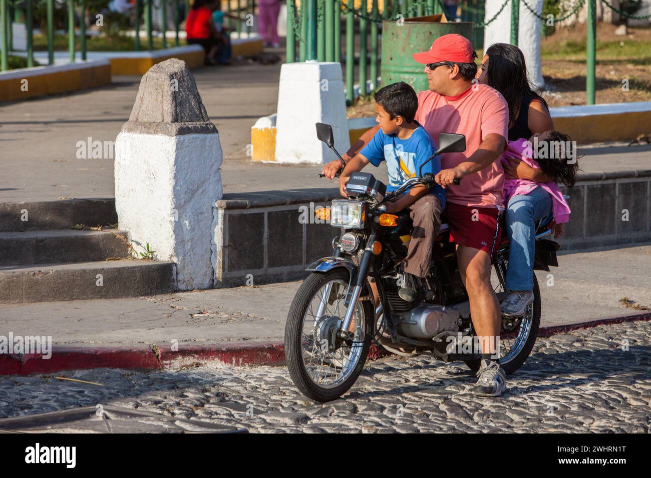 Antigua, Guatemala. Père, mère et deux enfants à moto, pas de casque. Banque D'Images