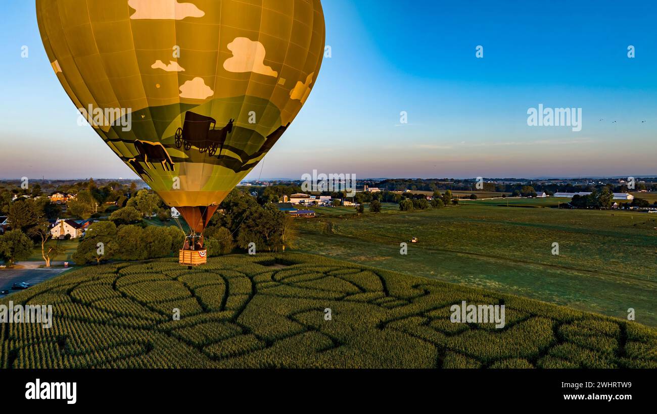 Vue aérienne d'une montgolfière dorée, tout juste lancée et flottant à travers un champ avec un labyrinthe de maïs Banque D'Images