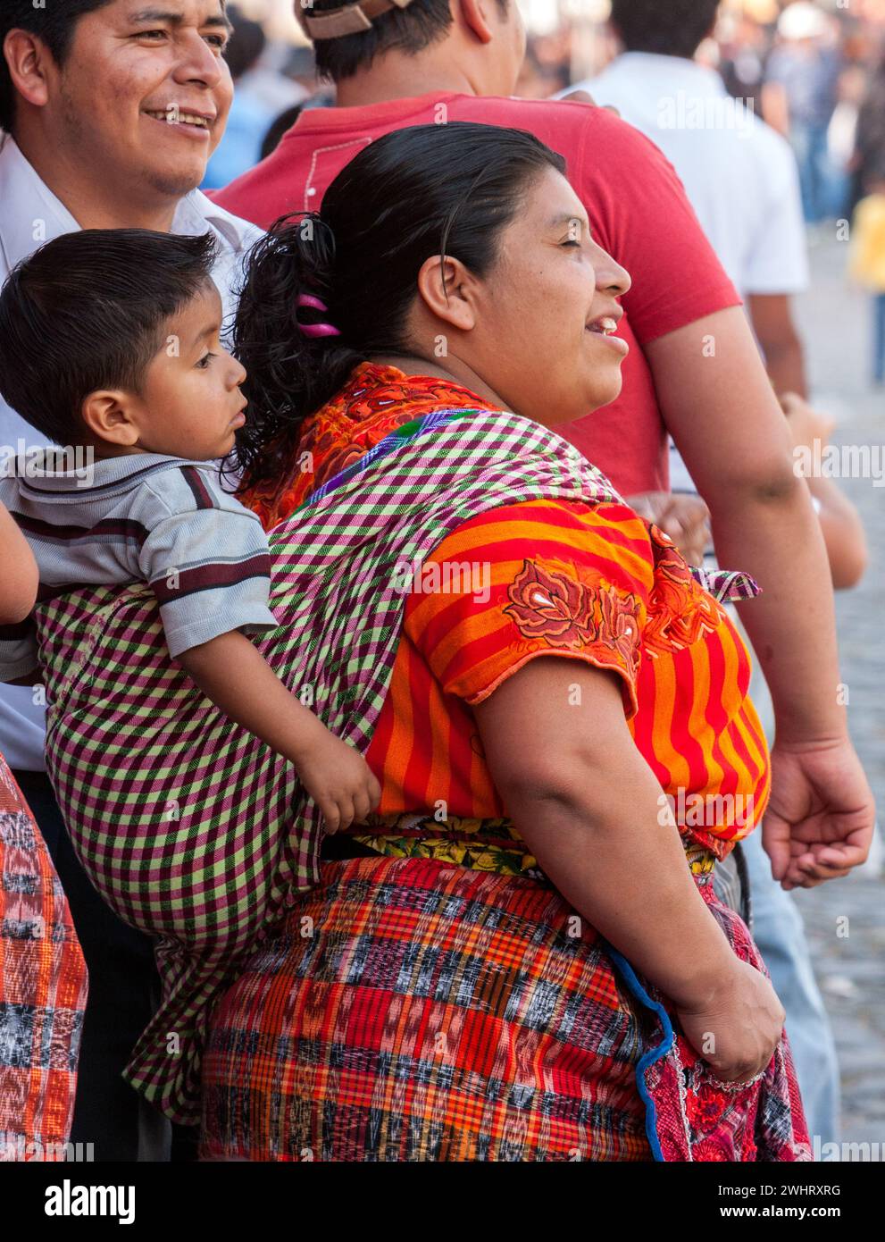 Antigua, Guatemala. Maya mère en vêtements traditionnels avec son fils sur son dos. Santa Semana. Banque D'Images