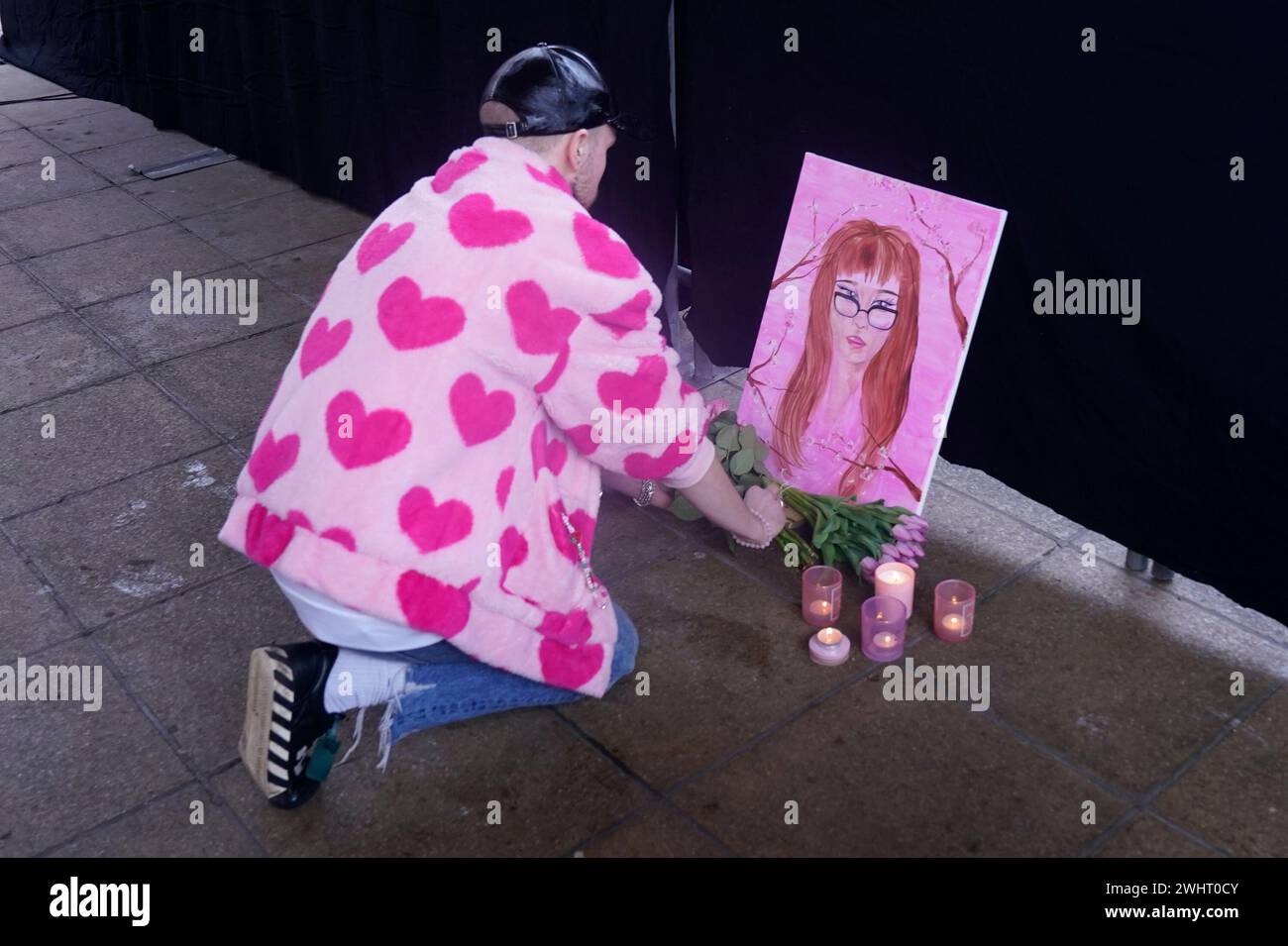 Sam Small, laisse quelques fleurs à côté d'une peinture qu'il a faite de Brianna Ghey, 16 ans assassinée, alors qu'il assiste à une veillée à Golden Square, Warrington, pour marquer le premier anniversaire de sa mort. Date de la photo : dimanche 11 février 2024. Banque D'Images