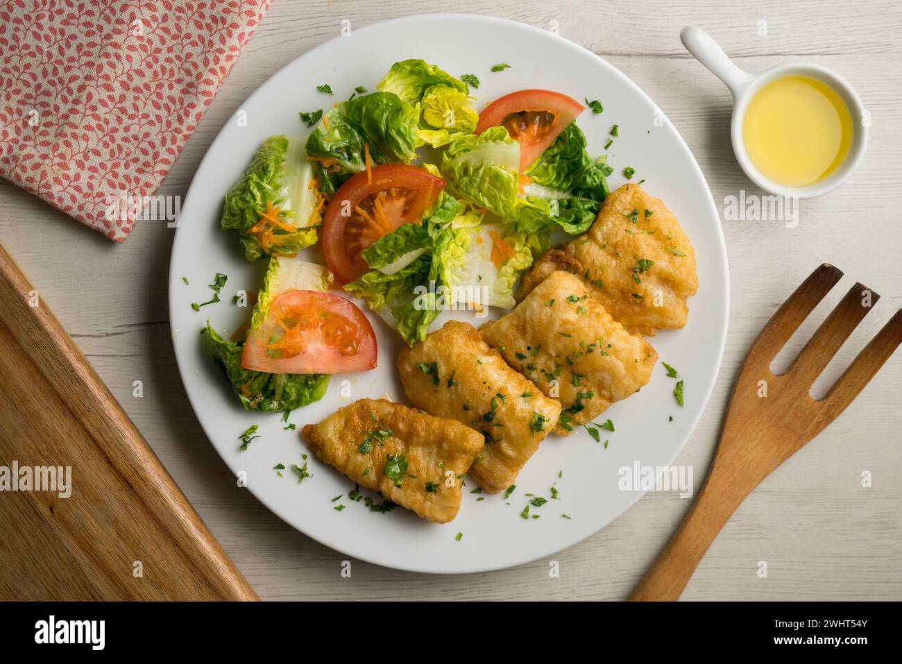 Poisson blanc pané servi avec une salade de tomates. Banque D'Images