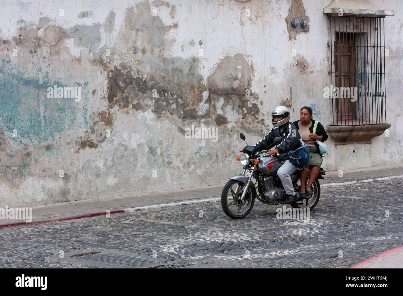 Antigua, Guatemala. Couple à moto, pas de casque sur passager. Banque D'Images