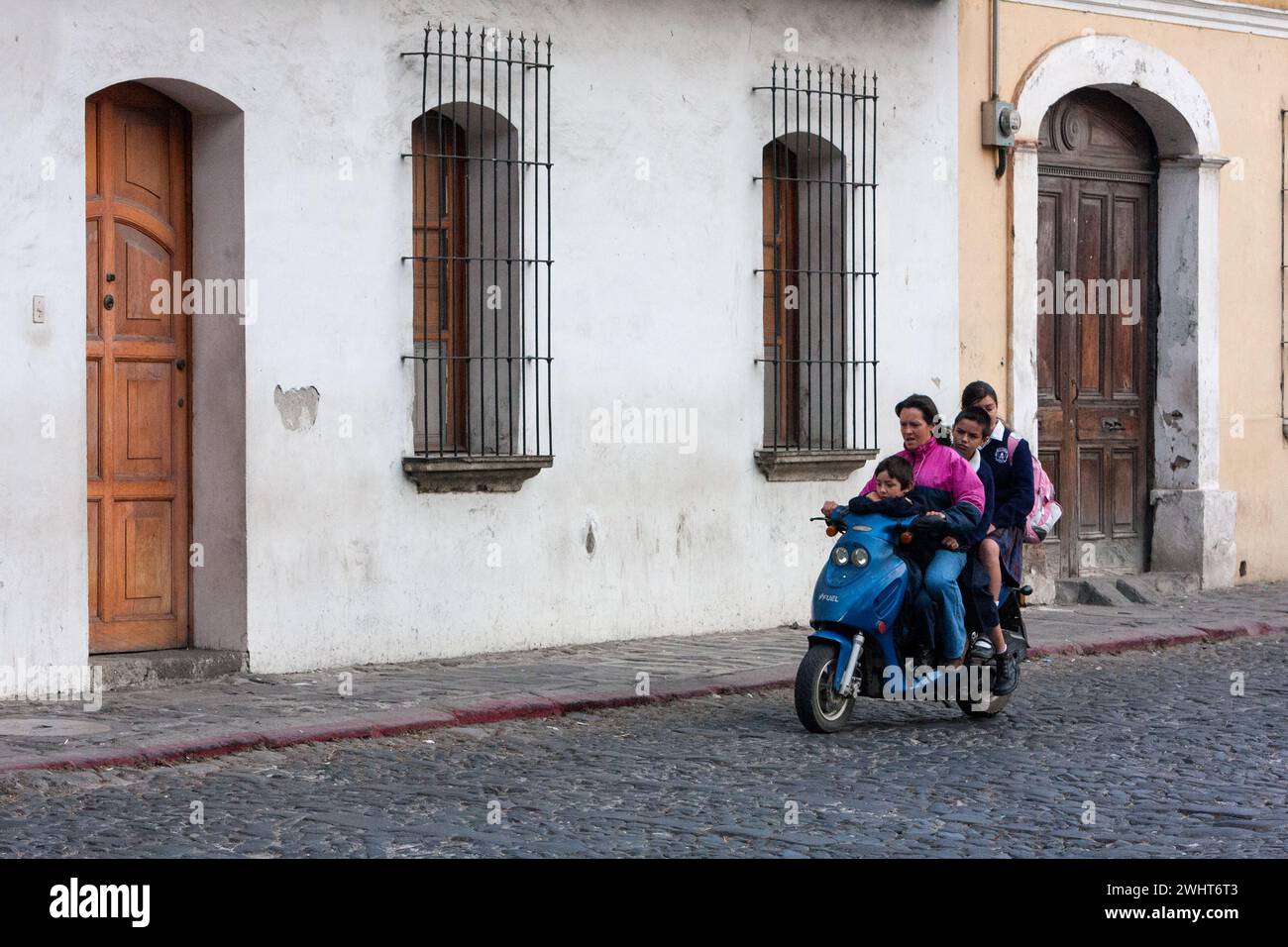 Antigua, Guatemala. Mère à moto avec trois enfants. Banque D'Images
