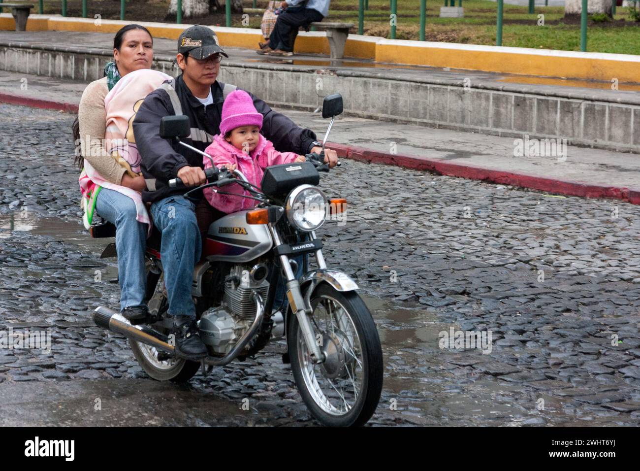 Antigua, Guatemala. Parents à moto avec deux enfants, sans casque. Banque D'Images
