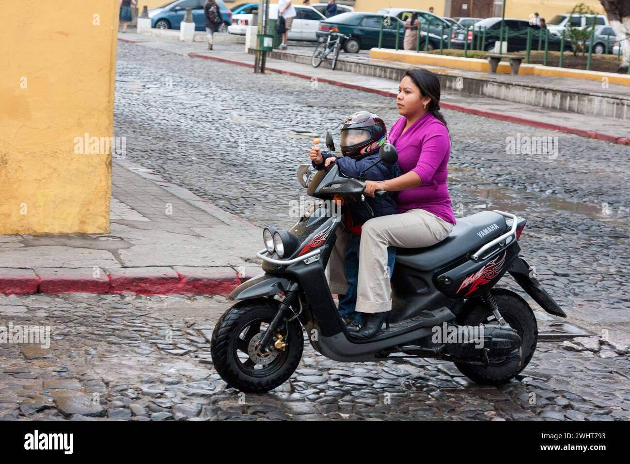 Antigua, Guatemala. Garçon avec Lollipop et Helmet à moto avec mère. Banque D'Images