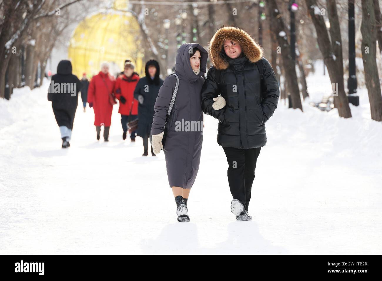 Couple heureux marchant par la rue de neige et parlant émotionnellement. Relation et loisirs en ville d'hiver Banque D'Images