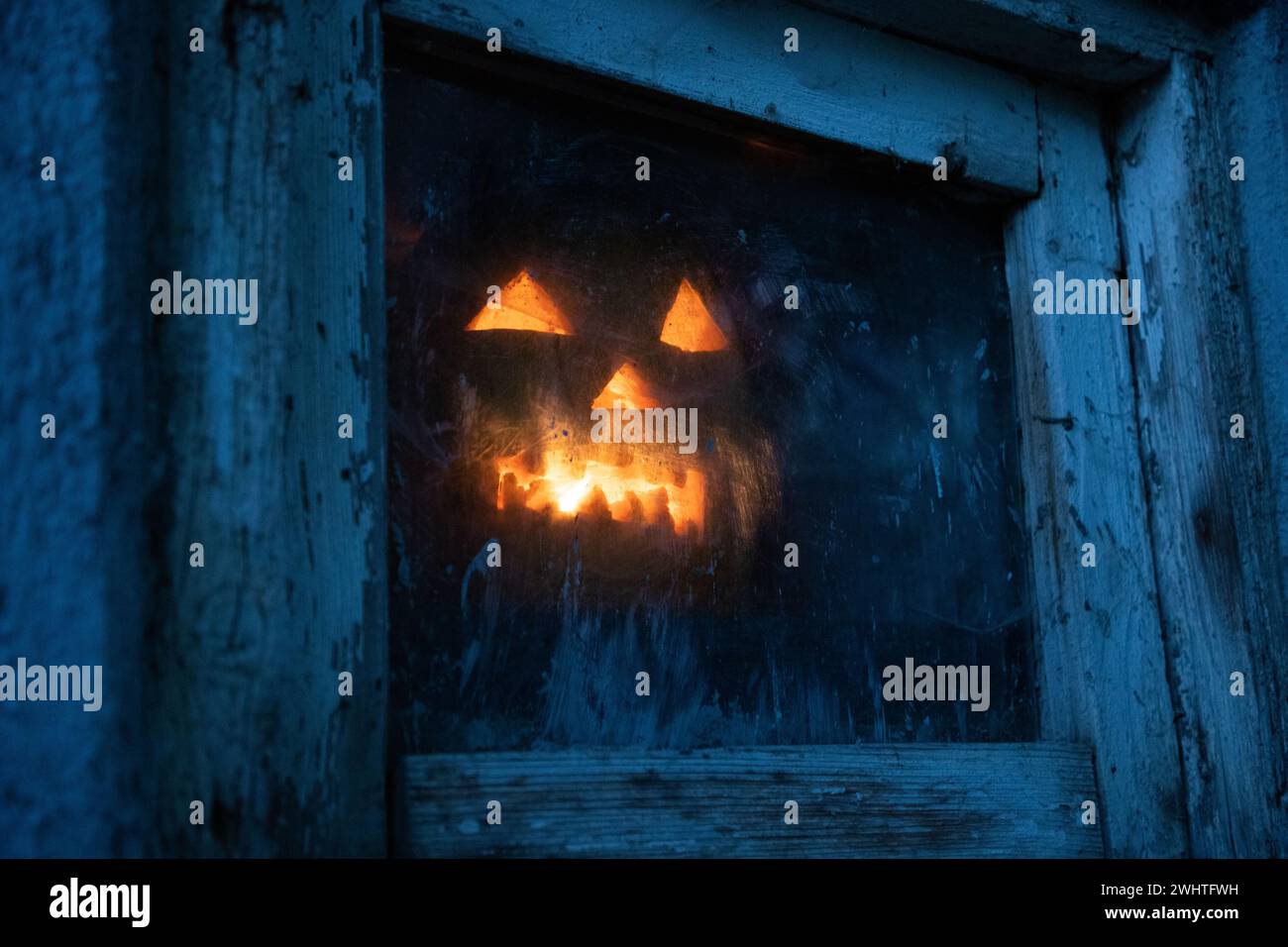 Citrouille d'Halloween effrayante dans la fenêtre la nuit Banque D'Images
