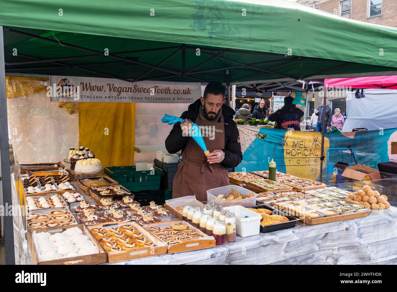 Stallholder remplissant des rouleaux de crème végétalienne sur une pâtisserie végétalienne et un étal de boulangerie, Cornhill Market, Lincoln City, Lincolnshire, Angleterre, ROYAUME-UNI Banque D'Images