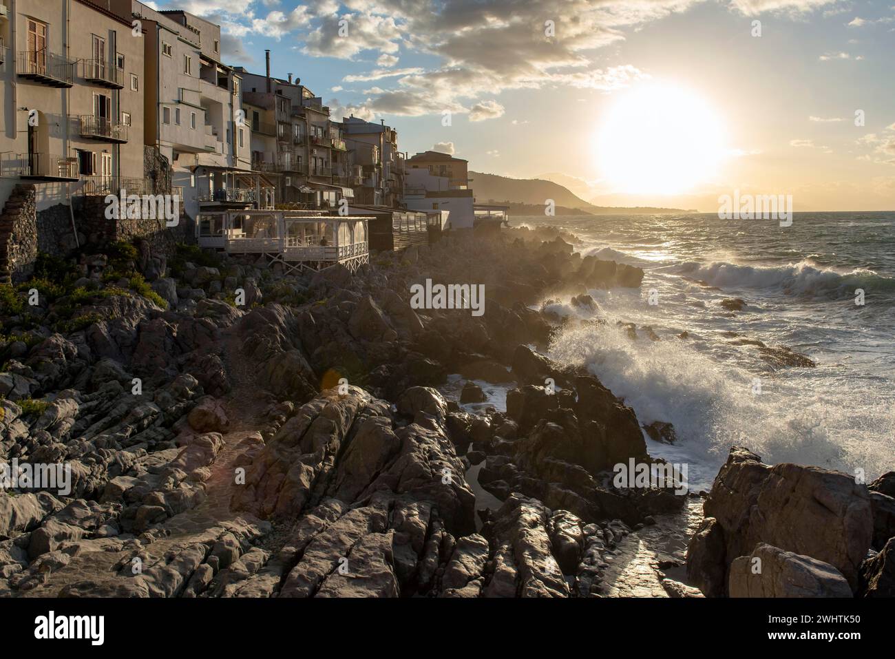 L'eau de mer s'écrase contre les falaises de la côte accidentée dans la ville de Cefalu, Sicile, Italie Banque D'Images