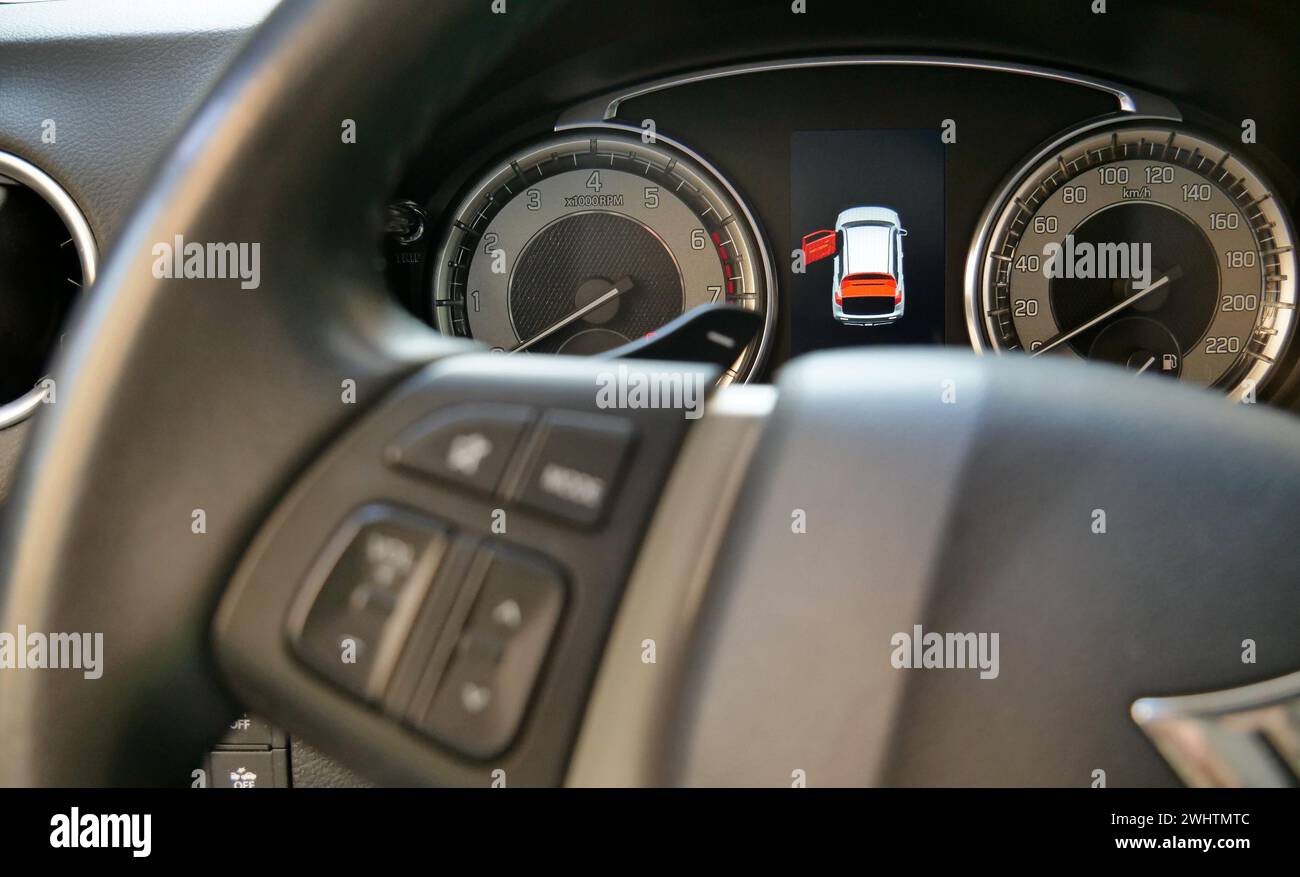 Tableau de bord de voiture avec icône de porte ouverte éclairée derrière le volant défocalisé Banque D'Images