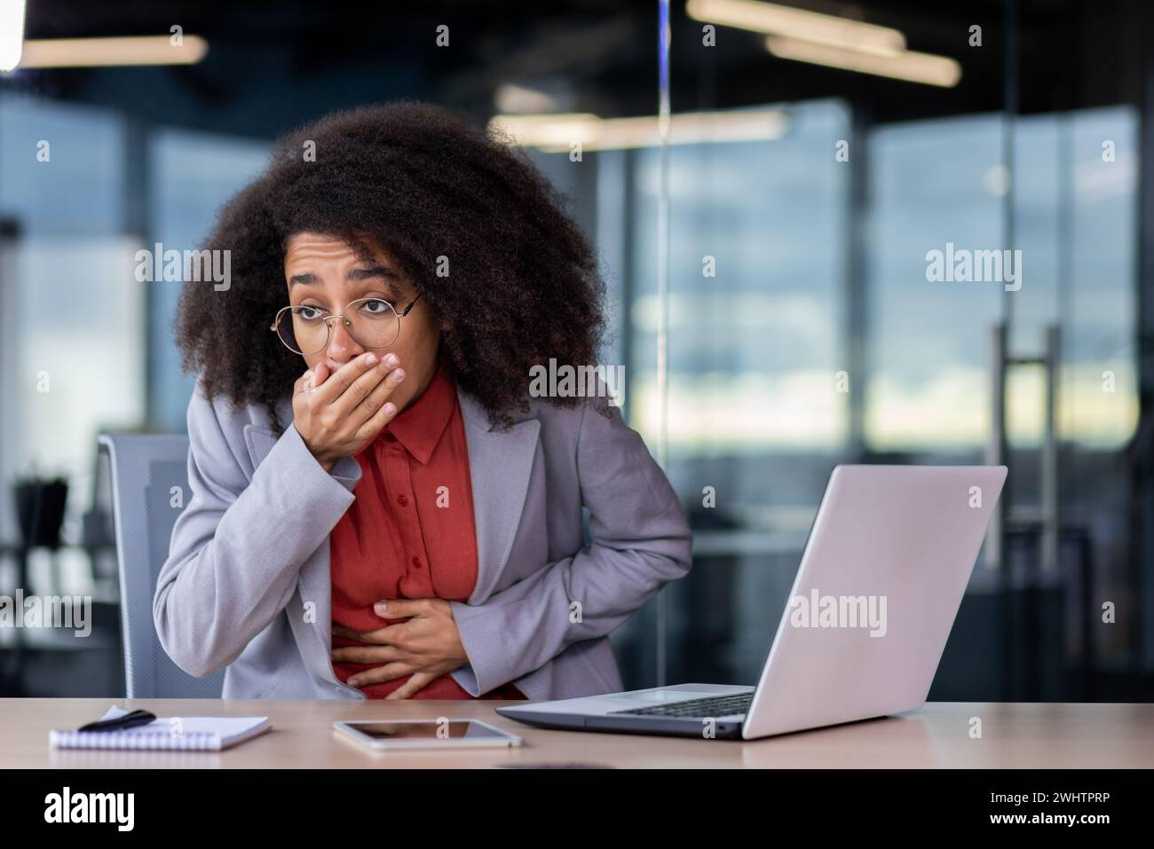 Femelle afro-américaine malade ayant une attaque de nausée sévère et couvrant la bouche avec la paume pour prévenir les vomissements. Dame malsaine souffrant de douleurs à l'estomac et de crampes tout en tenant le ventre à l'espace de travail. Banque D'Images