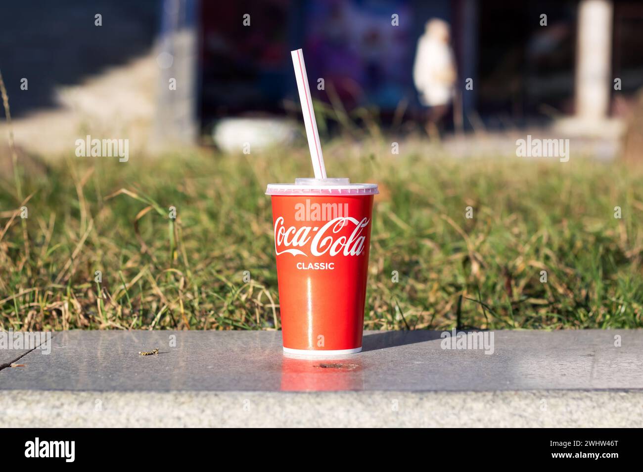 Biélorussie, Minsk - 29 octobre 2023 : verre de Coca Cola sur trottoir près de l'herbe Banque D'Images