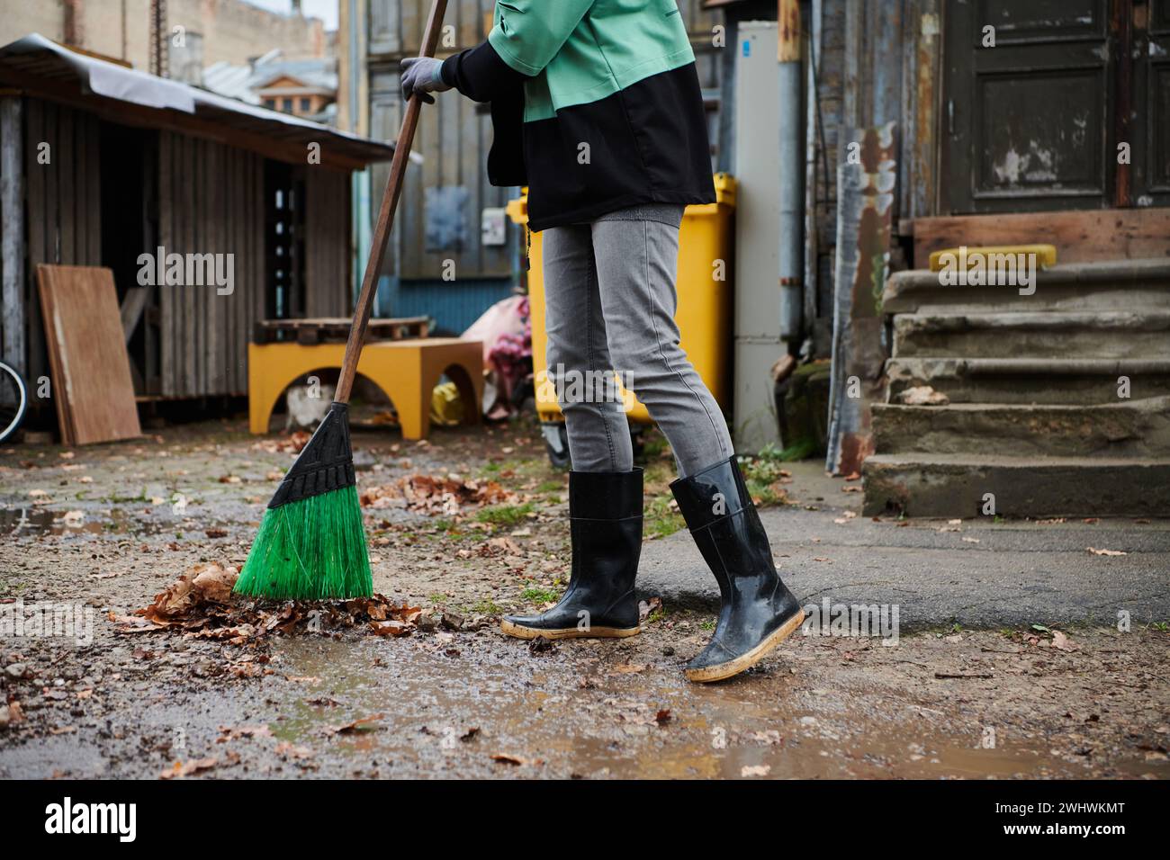 Une femme entretient diligemment le jardin en recueillant de vieilles feuilles sèches, créant une scène pittoresque de soins en plein air et saisonniers Banque D'Images