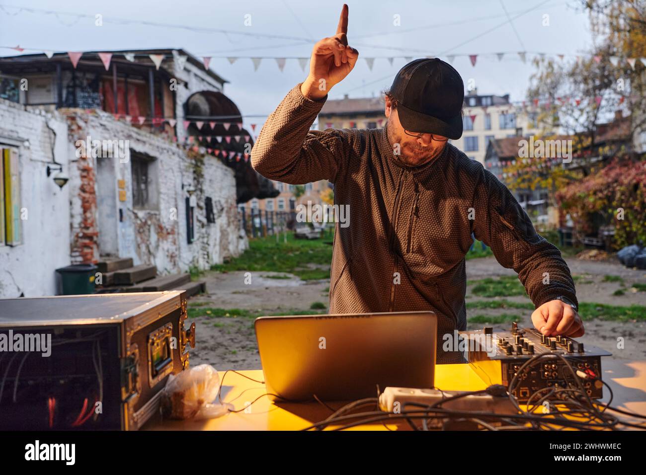 Un jeune homme divertit un groupe d'amis dans l'arrière-cour de sa maison, devenant leur DJ et jouant de la musique dans une ambiance décontractée Banque D'Images