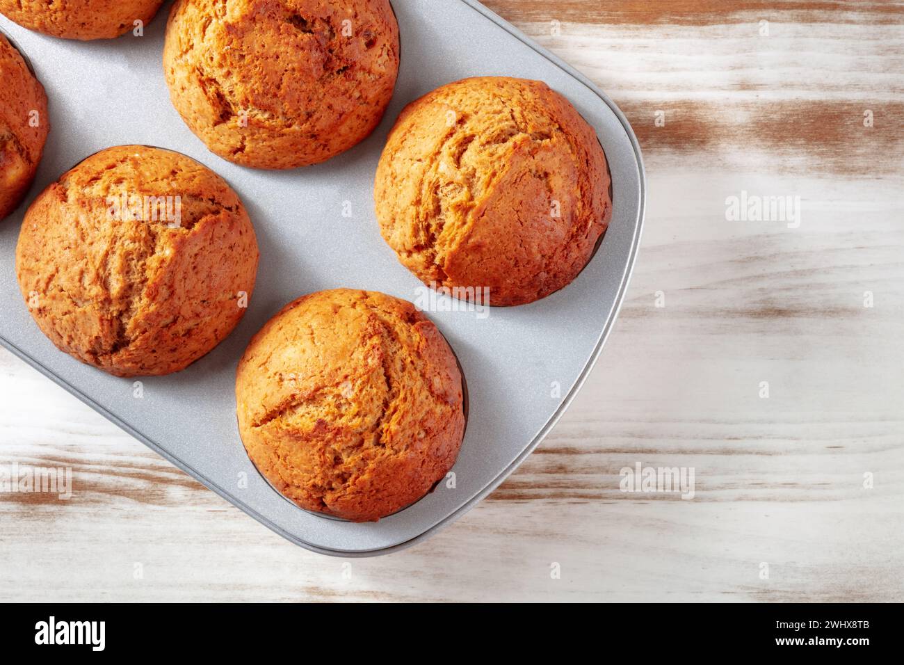 Muffins à l'orange dans un moule à muffins sur une table de cuisine rustique en bois, cuisson facile Banque D'Images