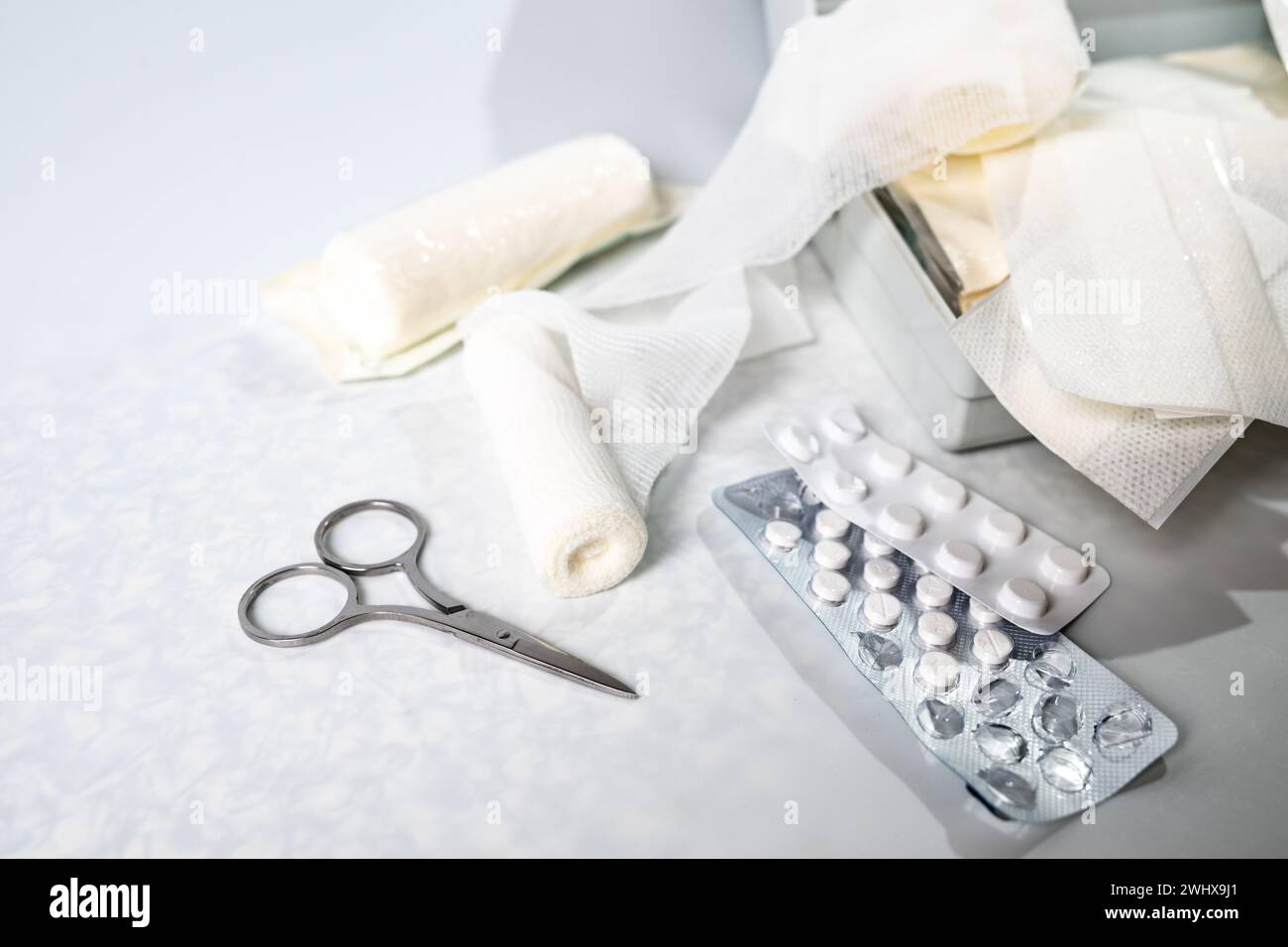 Fournitures médicales comme des bandages, des emplâtres, des pilules et des ciseaux d'une trousse de premiers soins ou d'un coffre de médecine à domicile sur un backgro gris clair Banque D'Images