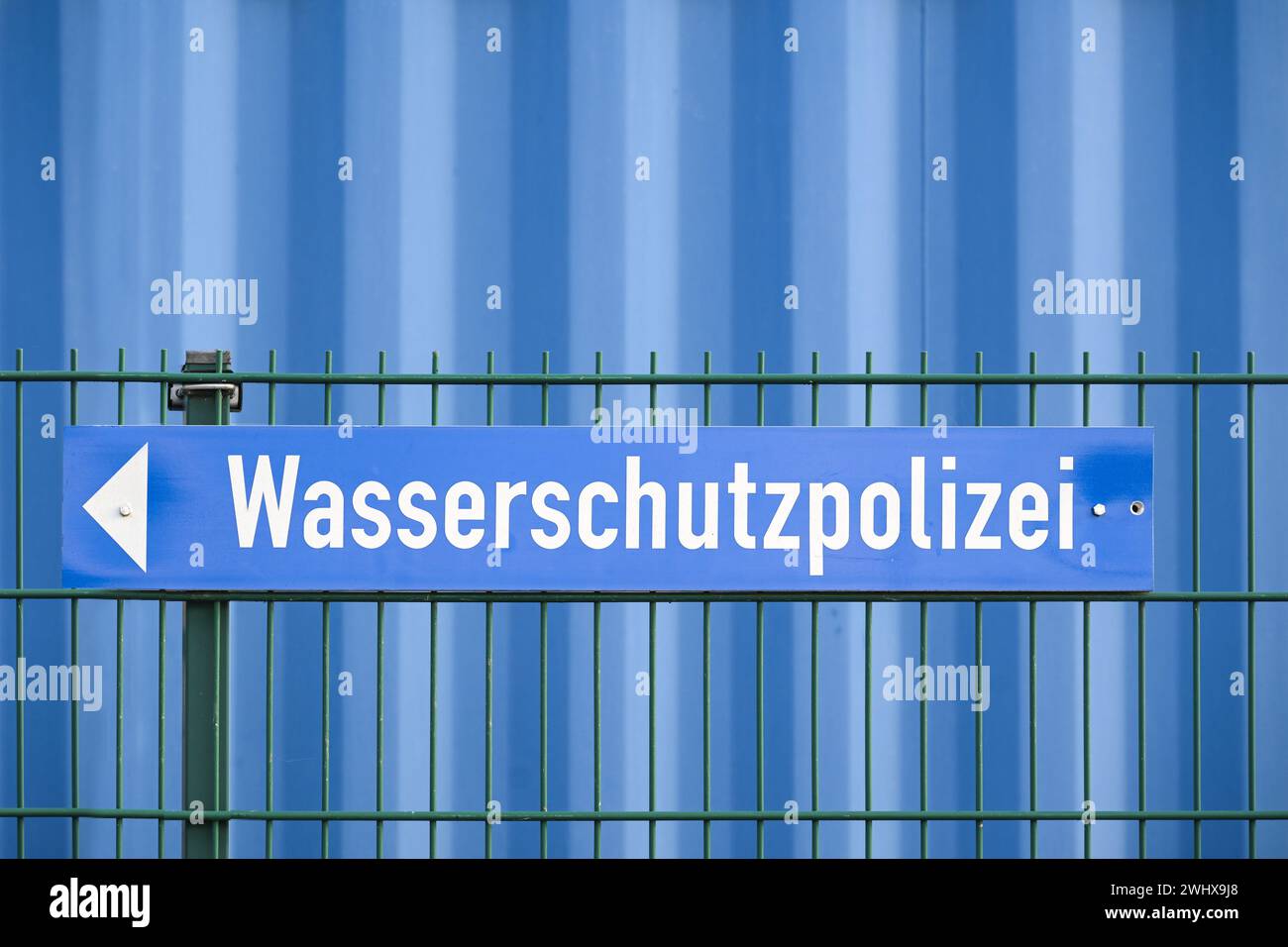 Signe avec le mot allemand Wasserschutzpolizei signifiant police de protection de l'eau sur une clôture devant un mur bleu, espace de copie Banque D'Images