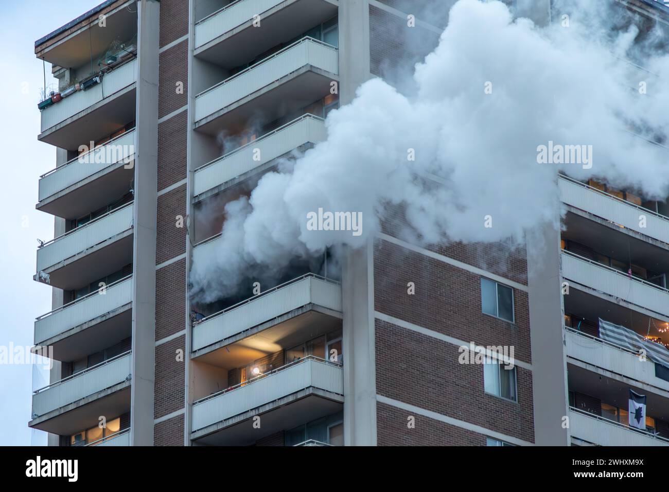 Toronto, Canada, 11 février 2024. Un homme, partiellement obscurci par la fumée, crie à l'aide depuis le coin d'un balcon d'un immeuble en hauteur au centre-ville de Toronto le dimanche 11 février 2024. Les pompiers ont pu asperger les flammes et le sauver. Colin N. Perkel/Alamy Live News Banque D'Images