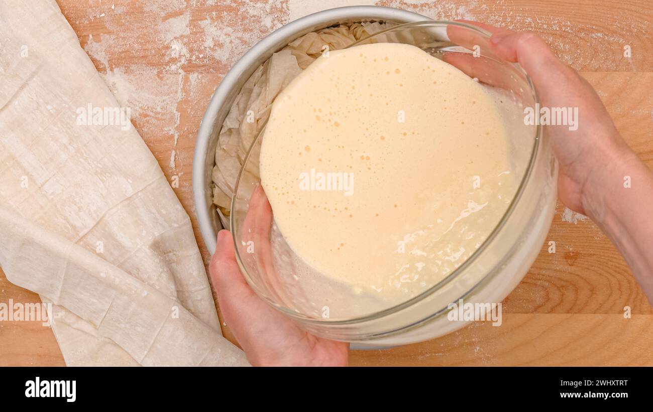 Chef versant la garniture crémeuse dans un moule de cuisson, processus de cuisson en gros plan Banque D'Images