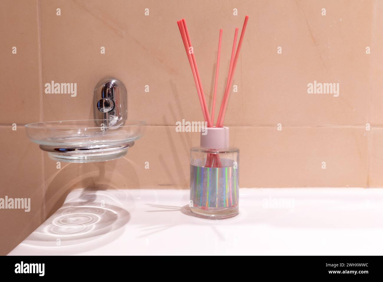 Pot en verre avec des bâtons d'arôme roses dans la salle de bain Banque D'Images