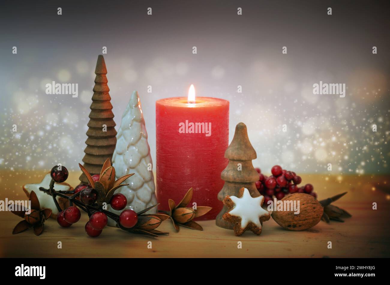 Décoration de Noël avec une bougie rouge, de petits sapins artificiels, des baies et des biscuits étoilés à la cannelle contre un bokeh étincelant Banque D'Images