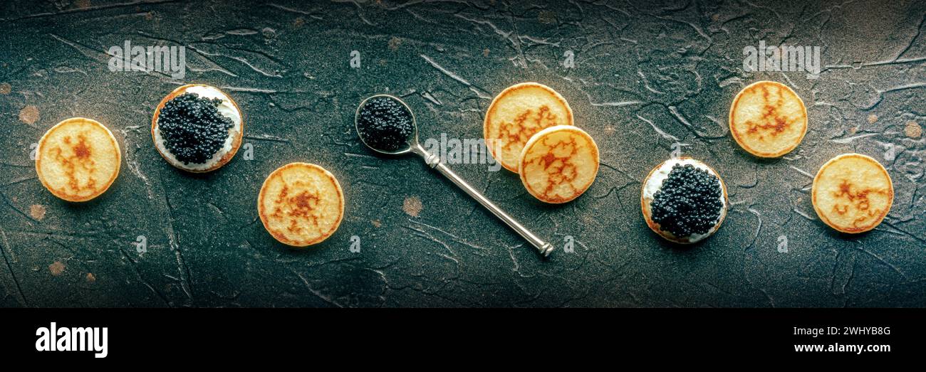 Blinis avec caviar noir et fromage à la crème panorama sur fond d'ardoise noire Banque D'Images