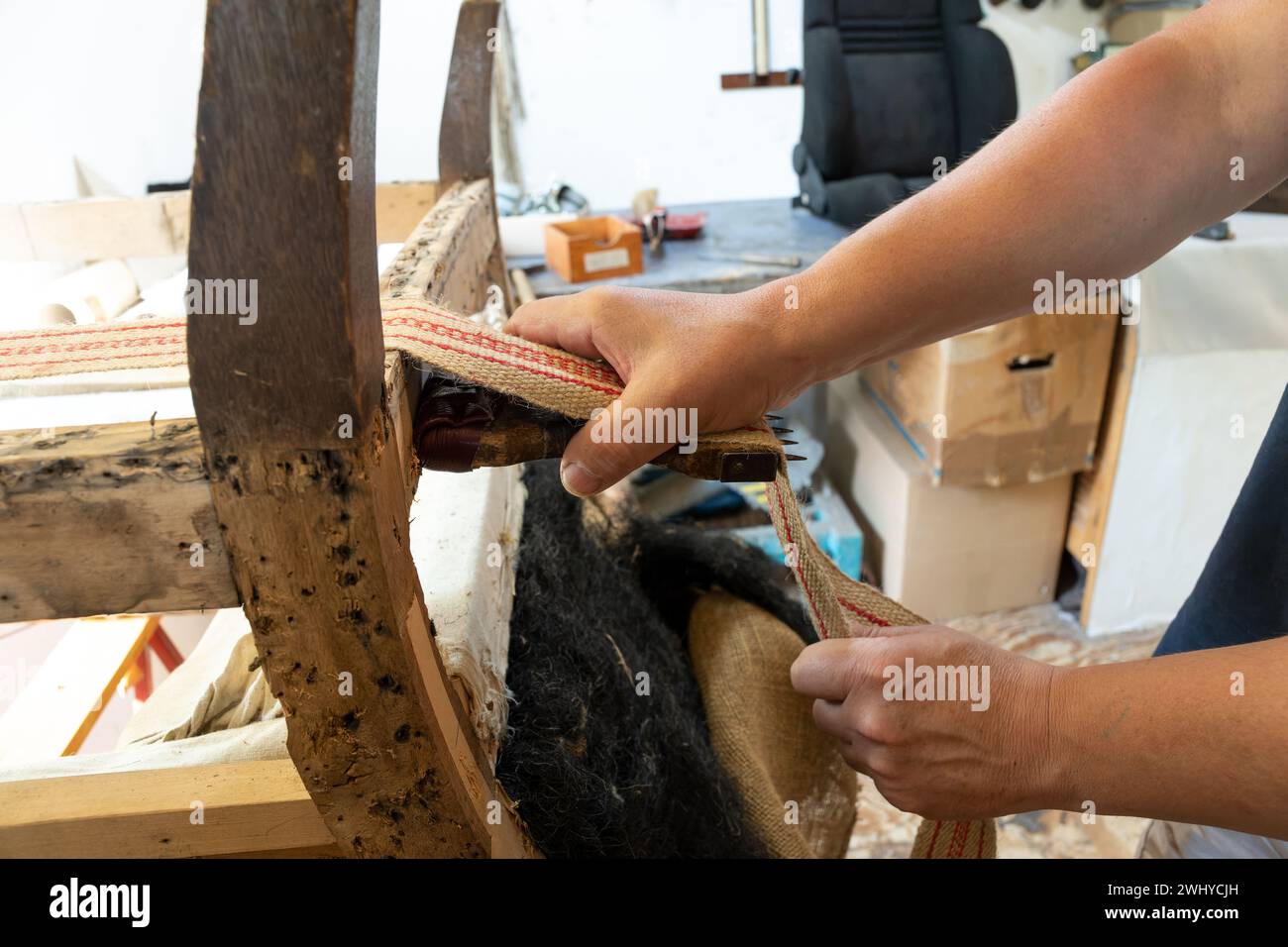 Rembourrage serrant une nouvelle sangle sur un vieux fauteuil, habileté artisanale traditionnelle pour préserver les meubles anciens, espace de copie, sélectionnez Banque D'Images