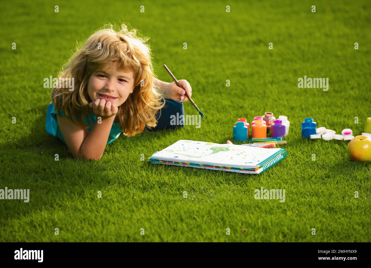 Les enfants créent artiste peint créativité vacances. Portrait d'un joyeux gamin souriant qui apprécie l'art et le dessin d'artisanat dans l'arrière-cour ou le parc de printemps. Enfants Banque D'Images