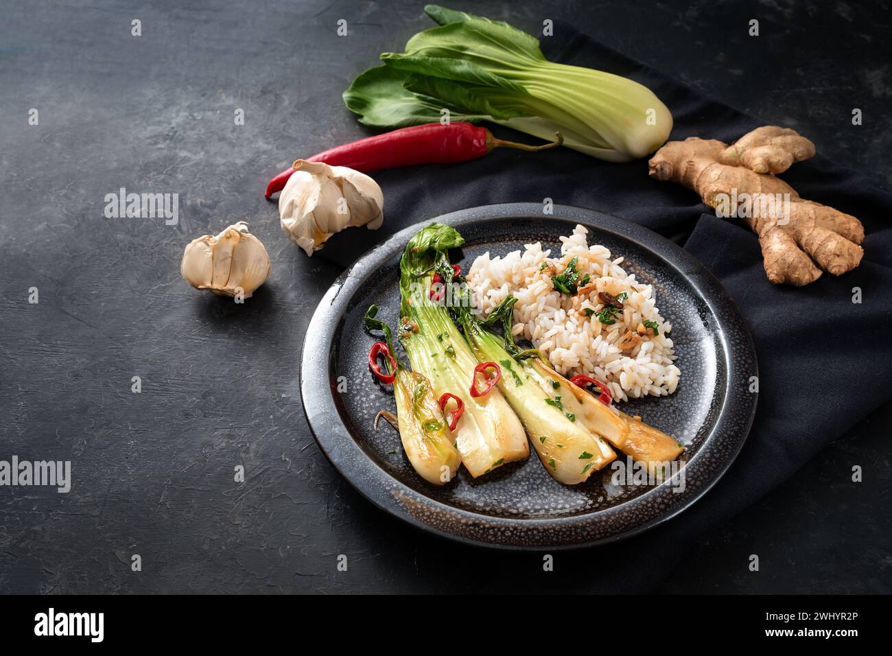 Repas végétarien de pak choi ou chou chinois, frit avec de l'ail, du gingembre, du piment rouge et des herbes, servi avec du riz sur un b Banque D'Images