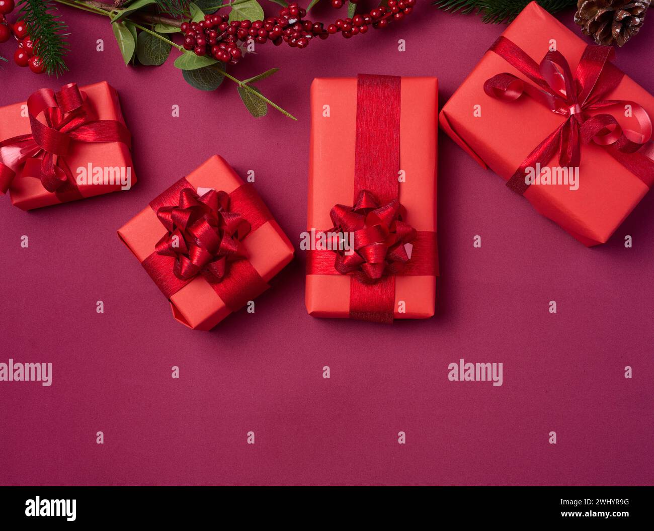 Décor de Noël, cadeaux enveloppés dans du papier rouge sur un fond rouge, vue de dessus Banque D'Images