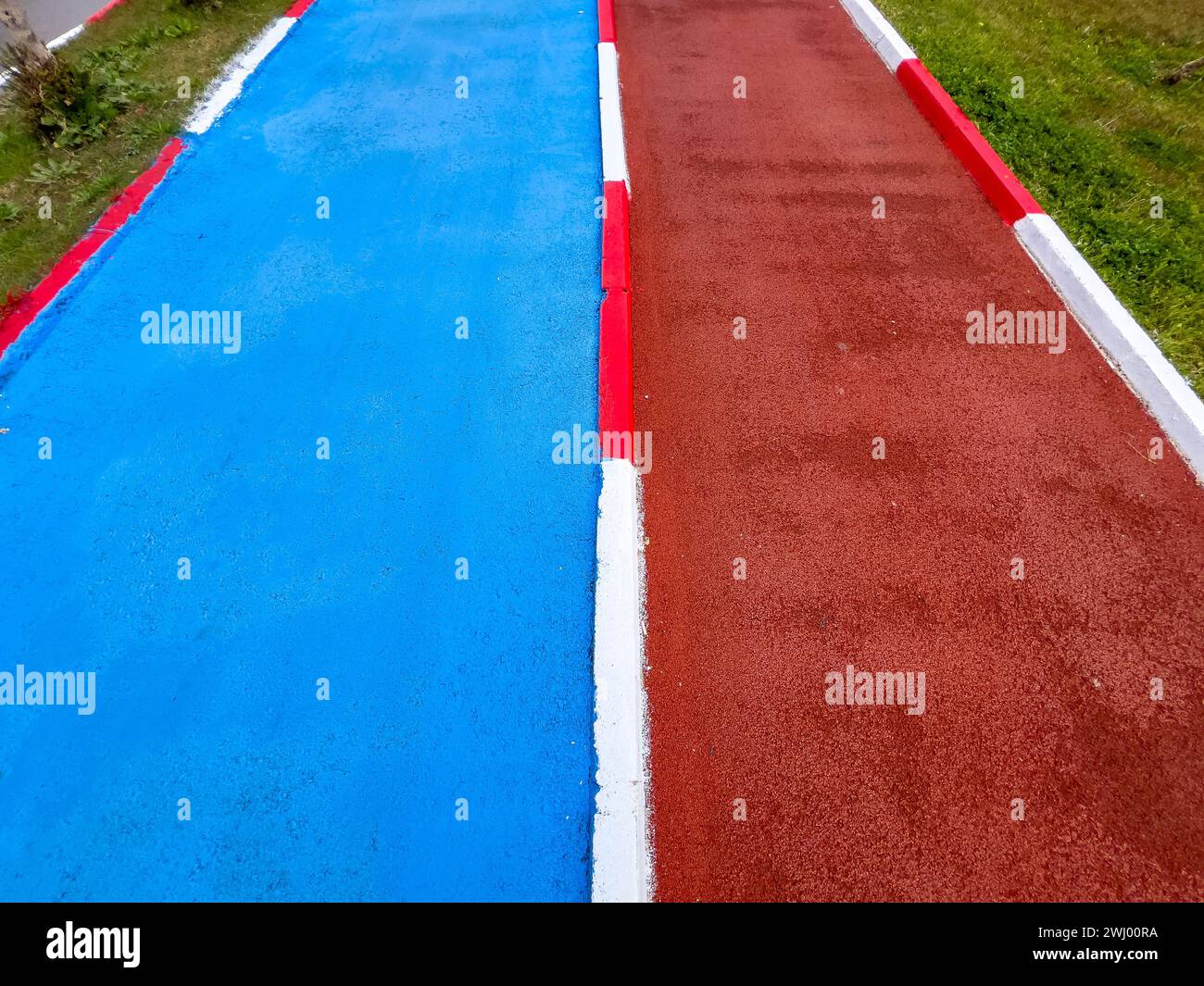 Piste cyclable bleue et piste de course rouge courent côte à côte à travers un parc public Banque D'Images