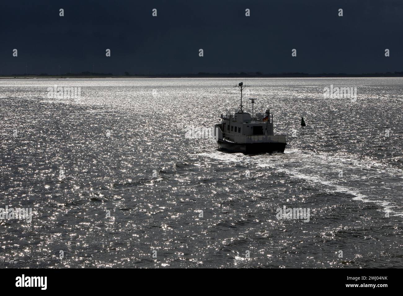 Navire sur la mer du Nord rétroéclairé avec un ciel sombre dramatique, Frise orientale, basse-Saxe, Allemagne, Europe Banque D'Images