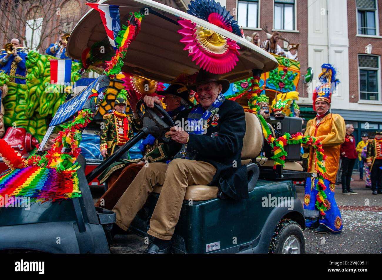 Nimègue, pays-Bas. 11 février 2024. Deux vieillards sont vus conduire une petite voiture décorée pour le Carnaval. À Nimègue, aux pays-Bas, le défilé du carnaval se compose d'un flotteur tiré par un véhicule électrique rempli des princes et princesses de l'année. Le reste de la parade se compose de gens habillés de costumes colorés et de groupes de musique. L'attraction principale chaque année est le costume que le maire de la ville Huber Bruls portera, cette année le thème était Flower Power. Crédit : SOPA images Limited/Alamy Live News Banque D'Images