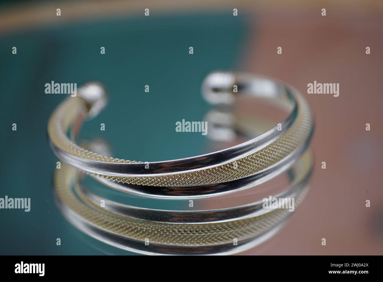 Une paire de bracelets bracelets vibrants reposant sur une table, tandis que l'autre main tient un bracelet unique Banque D'Images