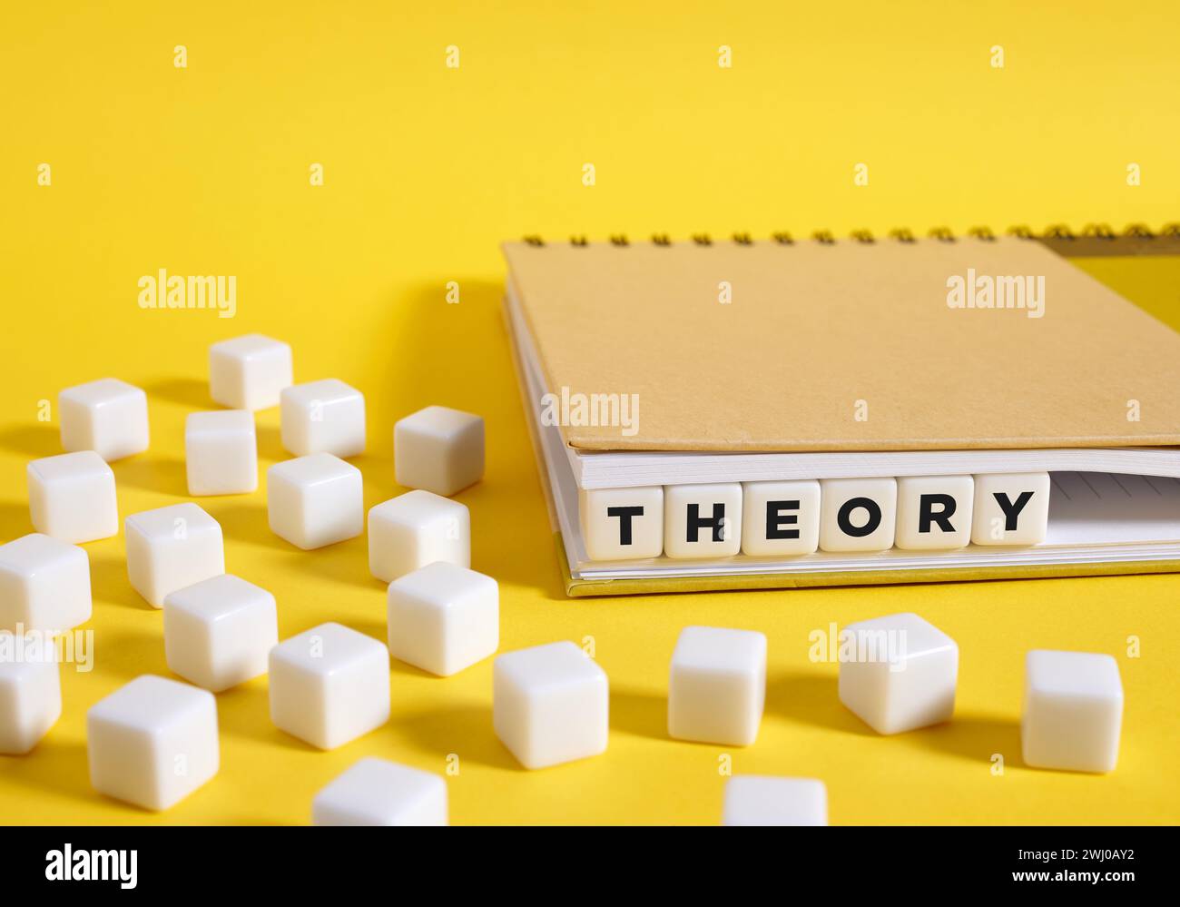 Le mot théorie écrit sur des cubes dans un cahier sur fond jaune. Formation théorique et concept de science. Banque D'Images