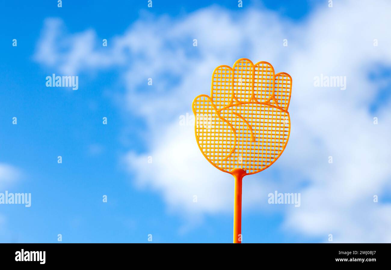 Symbole de geste levez la main. Swatter de mouche en plastique jaune sur fond bleu de nuage de ciel. Banque D'Images