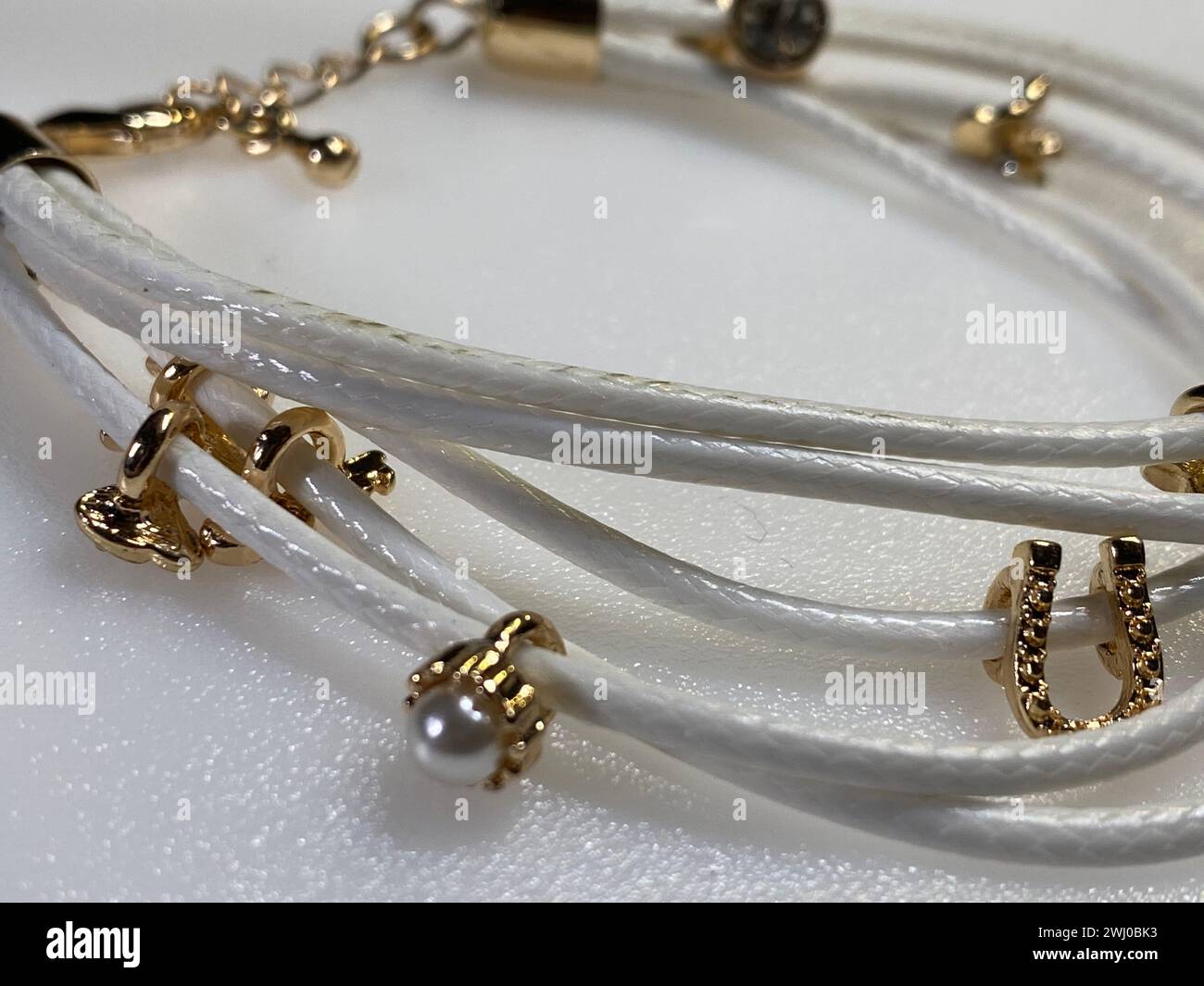 Trois bracelets blancs ornés de breloques dorées Banque D'Images