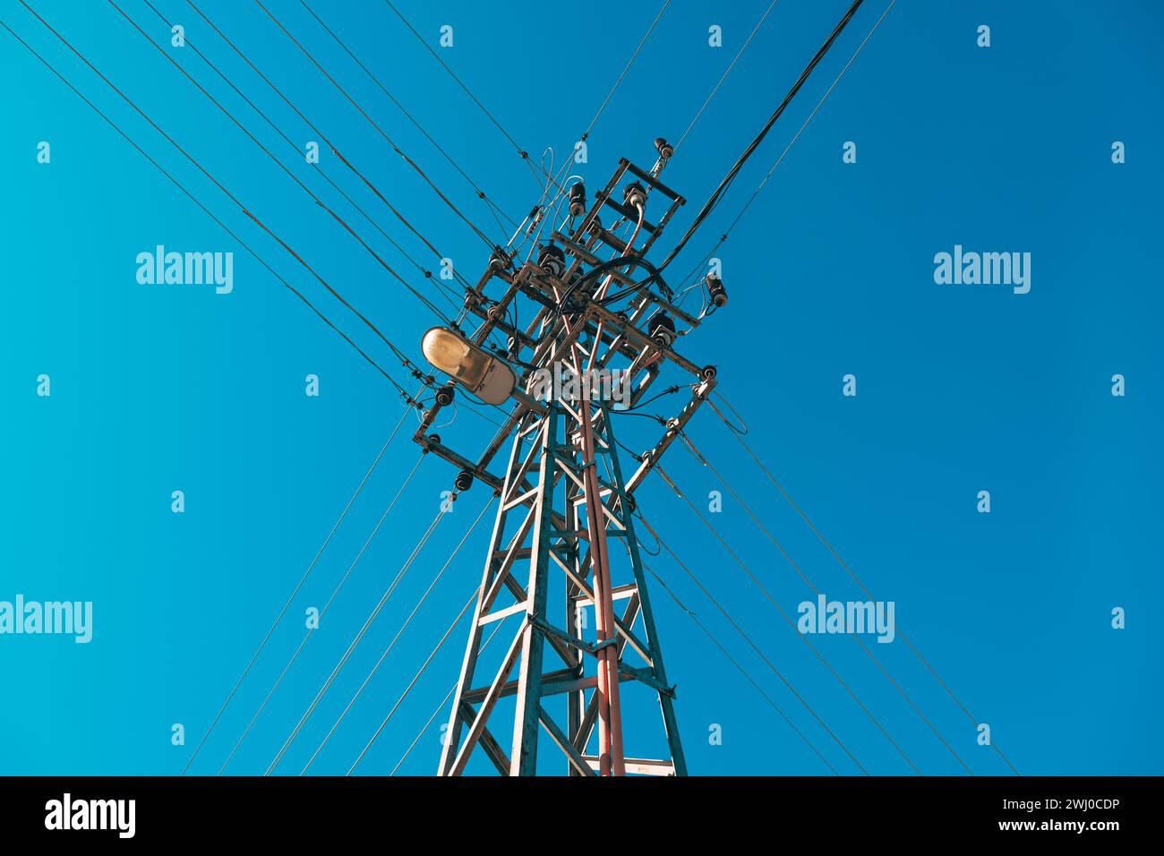 Poteau électrique avec des fils aériens et lampadaire contre le ciel bleu Banque D'Images