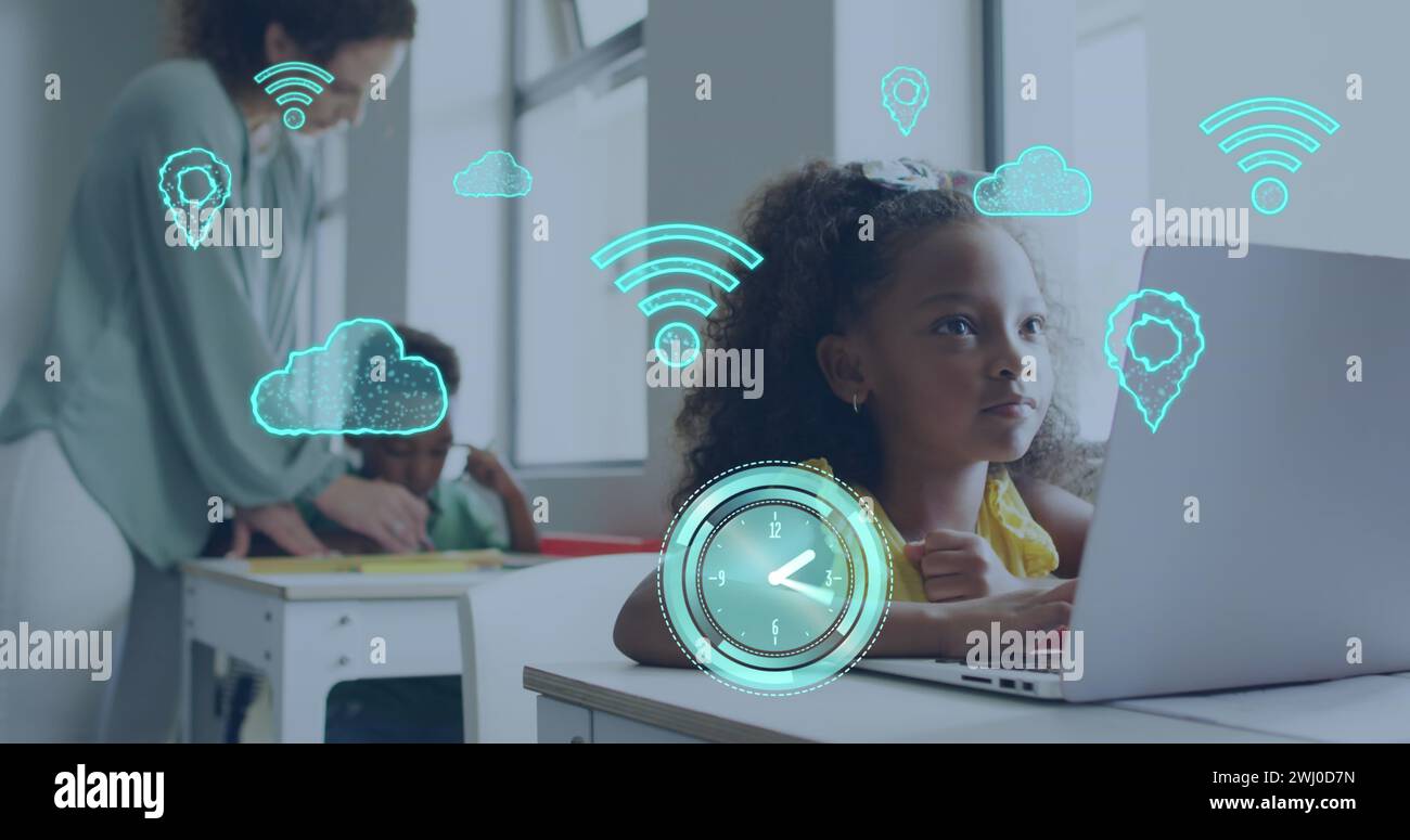 Image d'icônes d'Internet sur l'écolière biraciale heureuse à l'aide d'un ordinateur portable dans divers Banque D'Images