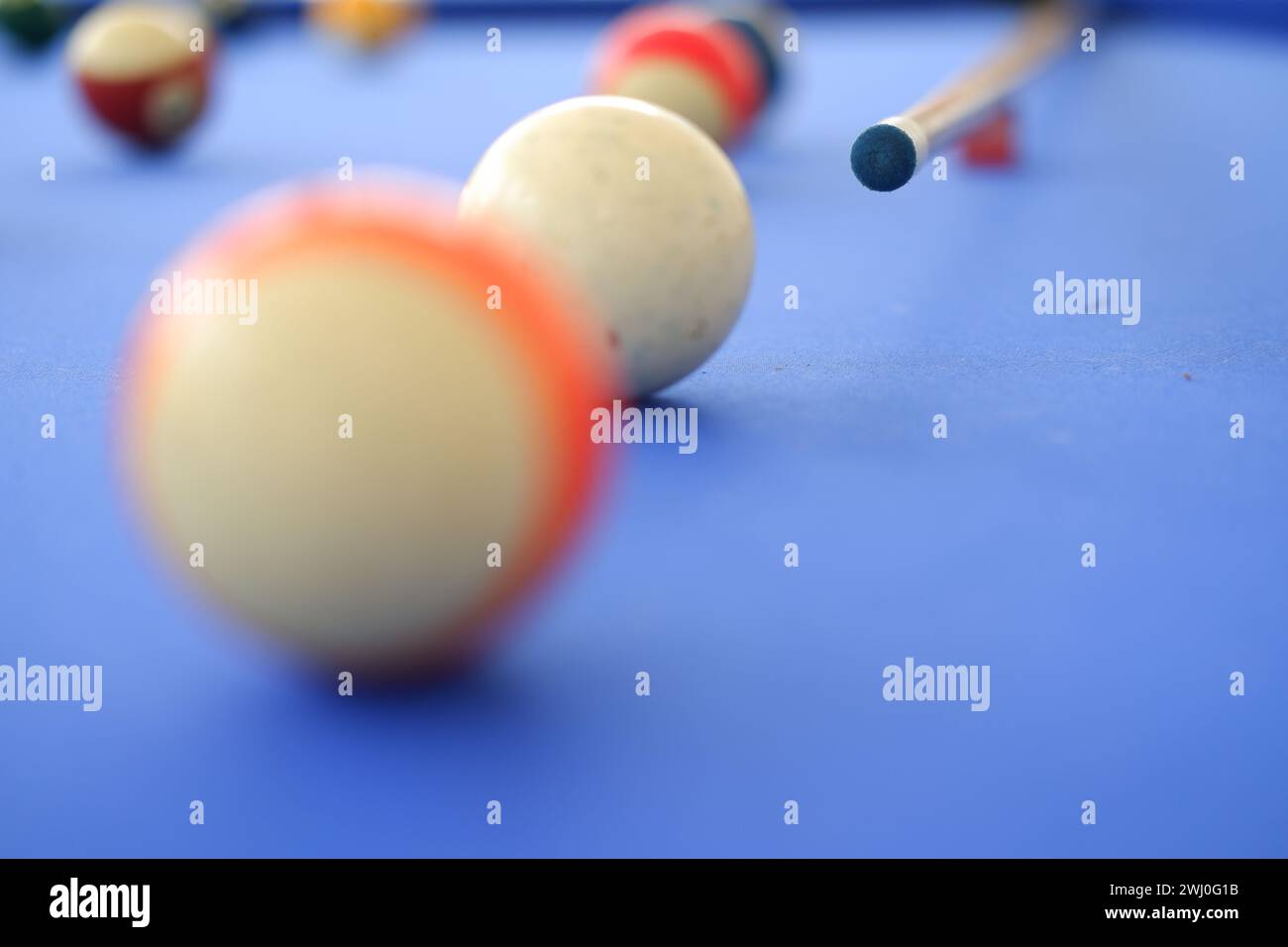 Boules de billard et queue de billard se rapprochent sur la table de billard bleu à l'extérieur dans une journée d'été ensoleillée. Repère sur la table sur le point de frapper la balle, photo bokeh Banque D'Images