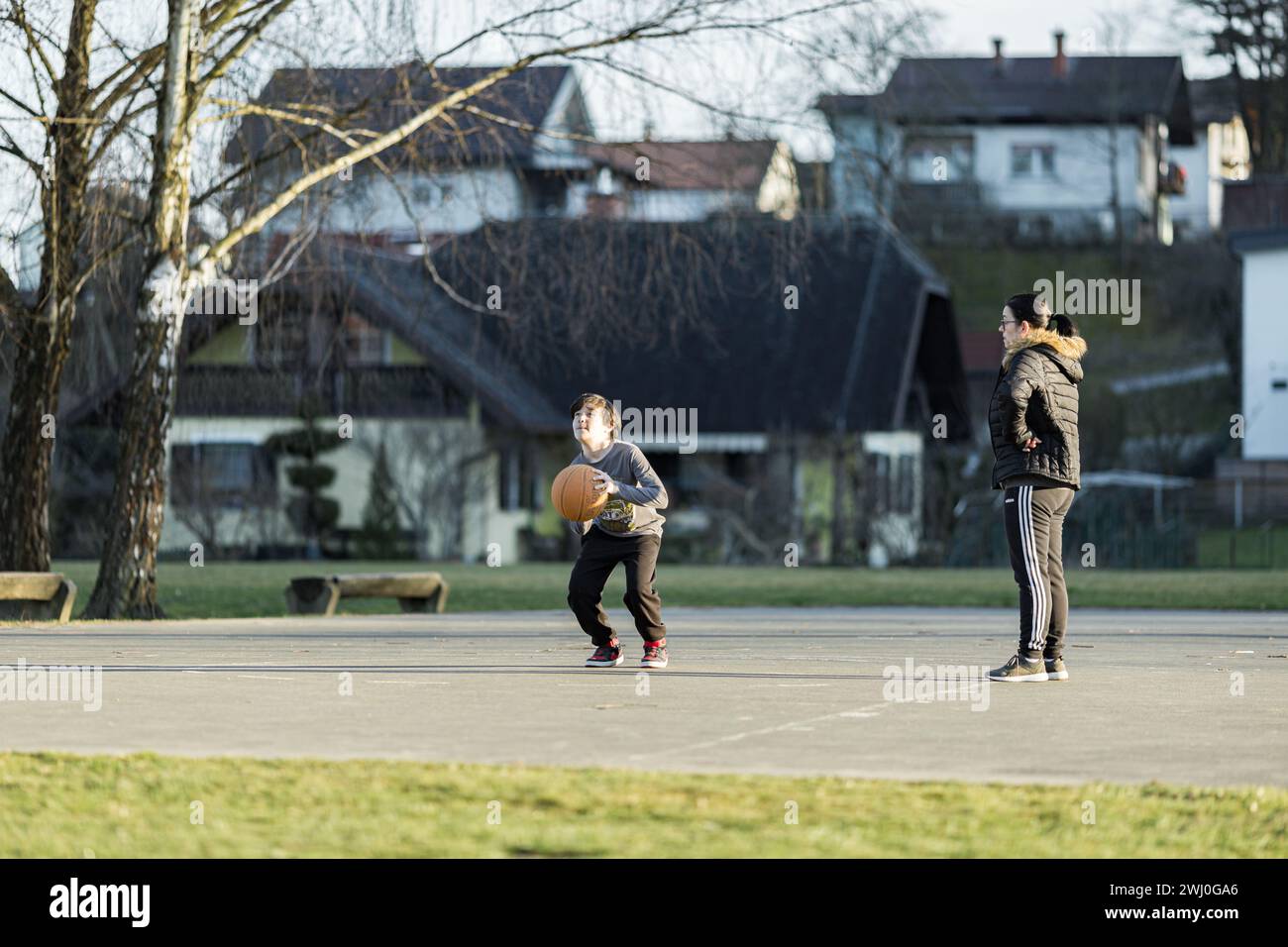 Une grand-mère et son petit-fils jouant au baksetbbal en plein air sur un court en automne Banque D'Images