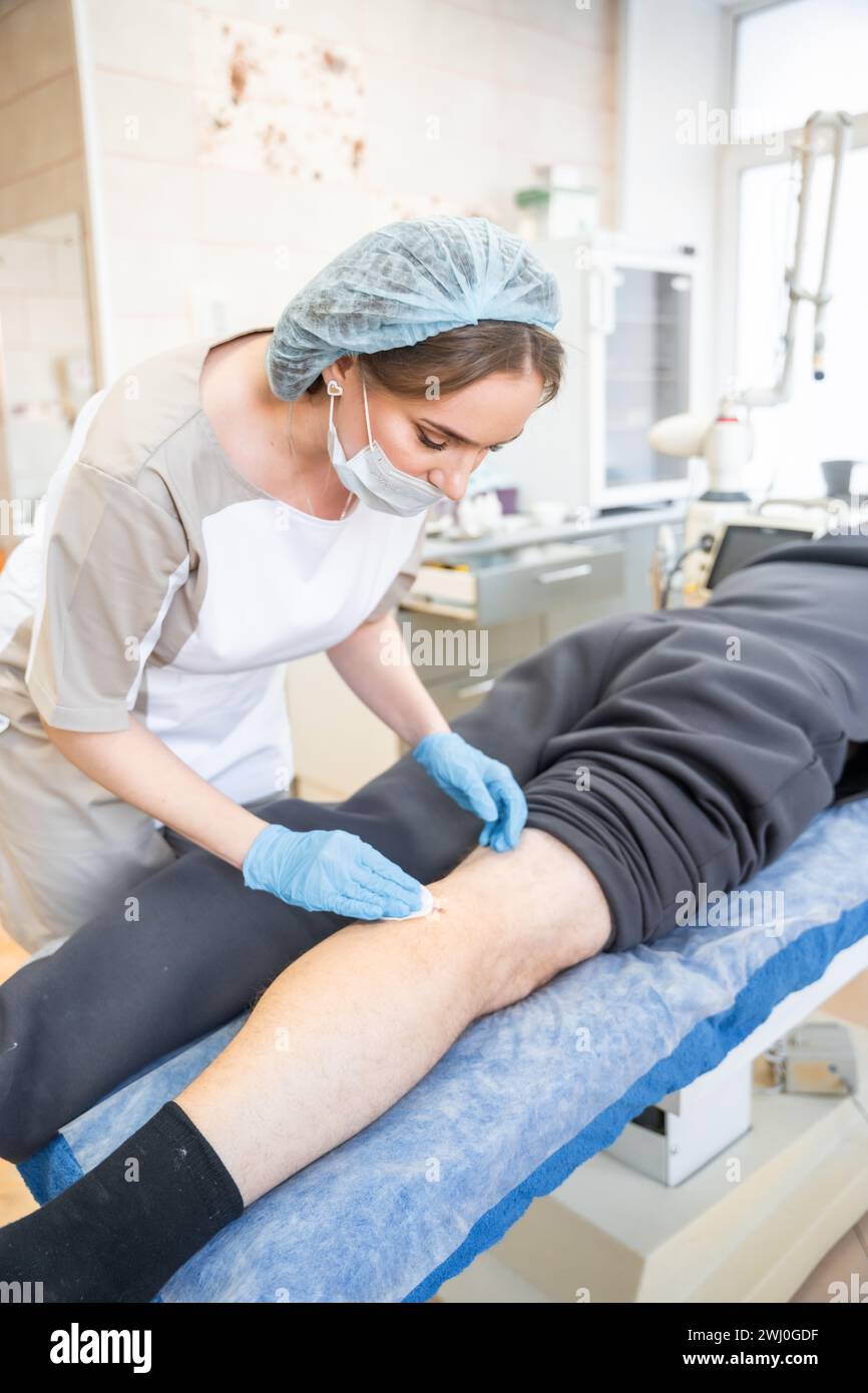 Travailleur médical effectuant le traitement des plaies et enlevant les points de suture Banque D'Images