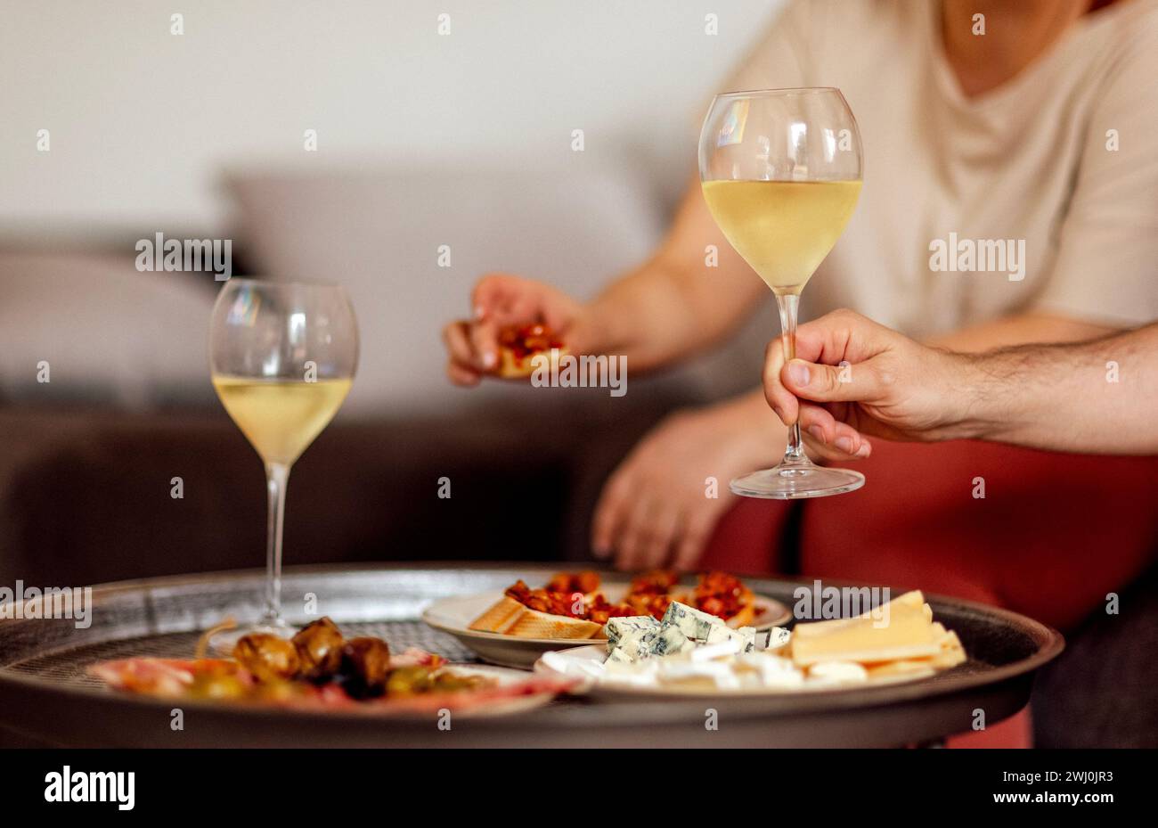 Deux verres de champagne frais et des assiettes avec divers en-cas sur une table basse ronde en métal Banque D'Images